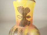 a yellow vase with a bird on it on a table