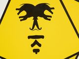 a close up of a yellow and black sign with a bird on it