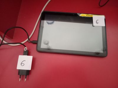 une tablette branchée à un chargeur posé sur la table