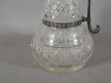 a glass pitcher with a metal handle on a table