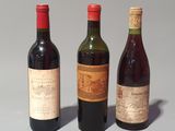three bottles of wine are lined up in a row on a gray surface