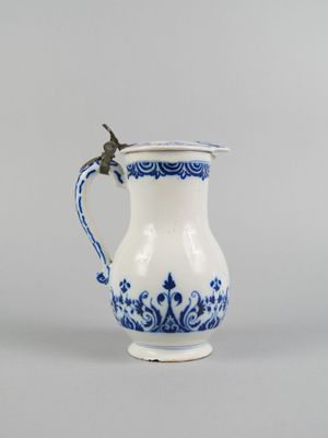 an old blue and white pitcher with a bird on the handle