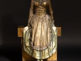 bronze statue of a woman sitting on a bench with a black background