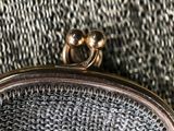 a silver purse with a gold ring on top of it