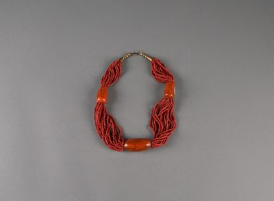 un gros plan d'un collier orné d'une perle rouge