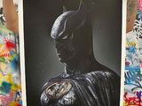 man holding up a black and white photo of batman in front of a graffiti covered wall