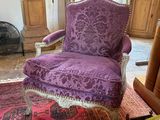 a purple chair sitting in a living room with a rug on the floor