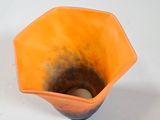 an orange bowl with a hole in it on a white surface
