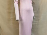 La robe est rose et a des manches longues.