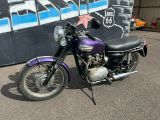 purple and black motorcycle parked in front of a graffiti covered wall