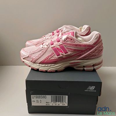 des chaussures de course roses et blanches posées sur une boîte noire posée sur une table