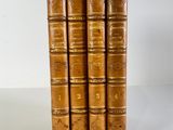 four old books are stacked on top of each other on a white surface