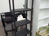 a black shelf with chairs and a table in front of a white wall