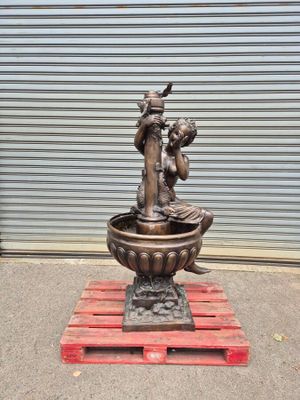 a statue of a woman sitting in a bowl on a pallet