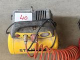 un compresseur d'air jaune et noir et un tuyau rouge