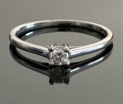 a close up of a diamond ring on a reflective surface