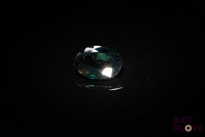 un gros plan d'un diamant vert à facettes posé sur une surface noire