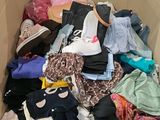 une boîte en carton remplie de vêtements, ainsi que des vêtements éparpillés par terre