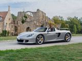 a silver sports car driving down the road in front of a castle