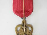 an old medal with a red ribbon hanging from it ' s side