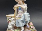 une figurine représentant une fillette avec un chien et un arrosoir