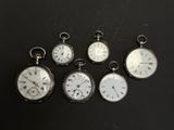 several different types of pocket watches are displayed on a black surface