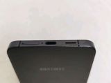 the back of a black samsung phone sitting on top of a white table