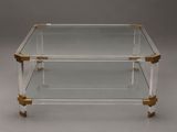 a clear glass and brass coffee table with two shelves