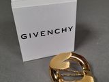 a close up of a gold brooch with a box in the background