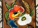 a picture of a tile with flowers and wheat on it