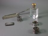 a bottle of perfume, a spoon, and other silver objects on a table