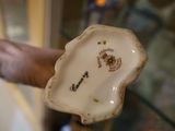 une main tenant une assiette en porcelaine sur laquelle figure une image