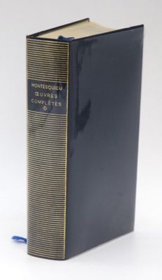 an old book sitting on top of a white table next to a blue book