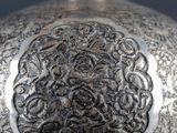 a silver vase sitting on a table with a black background