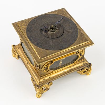 une horloge posée sur un support sur une surface blanche