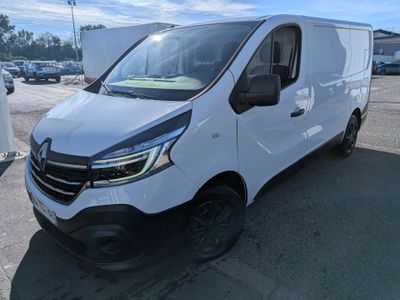 une camionnette blanche garée sur un parking, avec d'autres véhicules en arrière-plan