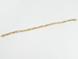 gros plan d'un bracelet en chaîne en or sur une surface blanche