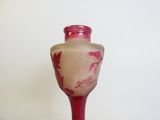 un vase en verre rose muni d'une anse rouge posé sur une table