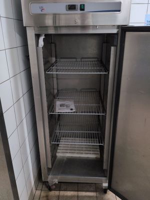 an empty refrigerator in the corner of a tiled room