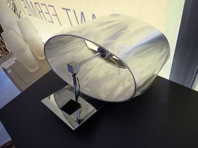 une table sur laquelle se trouve une lampe, avec une pancarte en arrière-plan