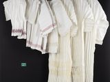 a group of white shirts hanging on a rack in front of a black wall