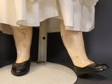 a mannequin of a woman wearing a white dress and black shoes