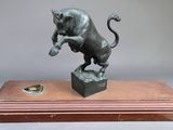 bronze statue of a lion on a wooden base on a gray background