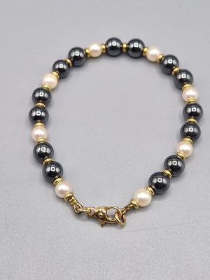 un bracelet de perles noires et blanches avec un fermoir en or