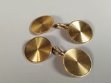 a pair of gold cufflinks on a white surface