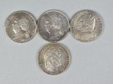 four different types of coins on a white surface