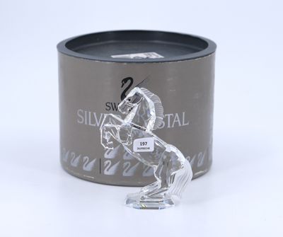a glass horse figurine sitting in front of a tin of silver metal