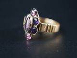 un gros plan d'une bague en or sertie de pierres violettes sur un fond noir