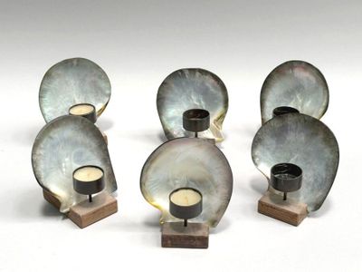 four metal candles are sitting on a wooden stand on a white surface
