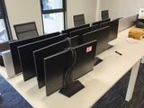 four computer screens on a table in a room